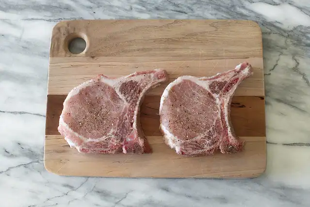 Apple cider pork chops prep: seasoning the chops.