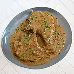 Creamy gravy with two cooked meat pieces garnished with chopped chives.