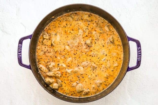 Adding the chicken, cream, seasonings, and broth to the sauté pan, making creamy Cajun chicken pasta with pancetta.