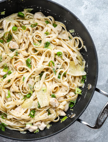 Closeup of creamy chicken pasta with artichokes and green onions.