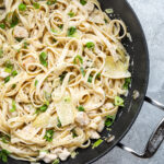 Closeup of creamy chicken pasta with artichokes and green onions.