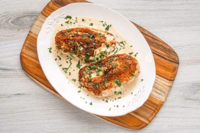 Breaded stuffed chicken breasts with creamy sauce and chopped herbs.