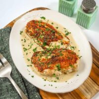 Baked seasoned fish fillets with herbs and creamy sauce.