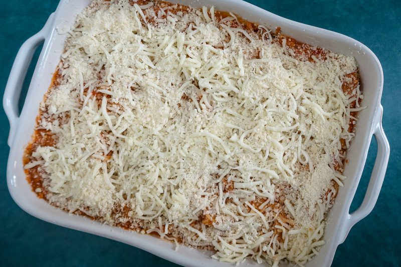 getting the spaghetti casserole ready to go in to the oven with a cheese topping