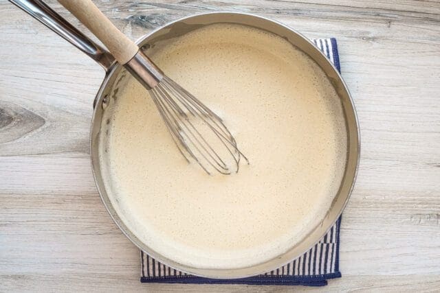 Creamy batter being whisked in a saucepan.