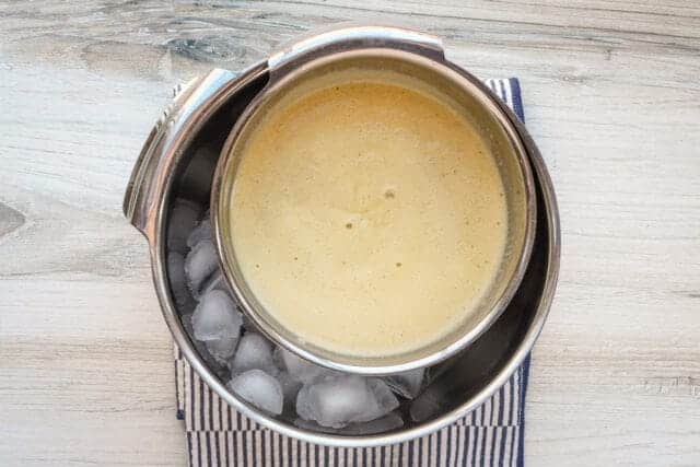 Creamy frothy beverage in a metal container over ice.