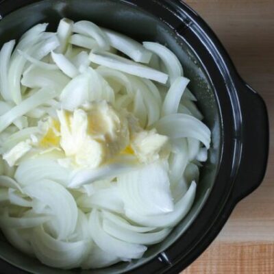 preparing slow cooker onion soup with onions and butter in the crockpot
