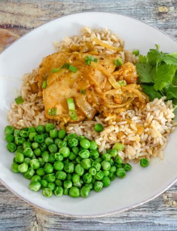 slow cooker chicken with curry flavor on a plate with rice and peas