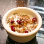 overnight oatmeal in a small bowl with dried cranberries and milk.