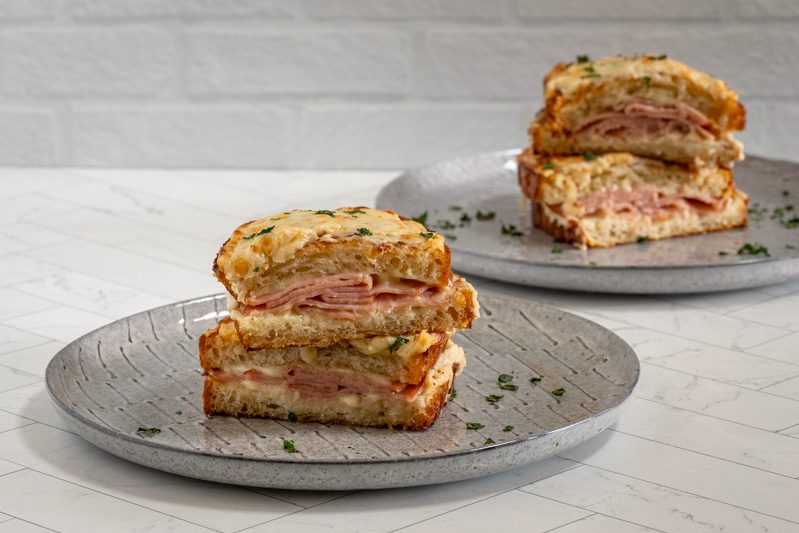 two croque monsieur sandwiches on plates with parsley garnish