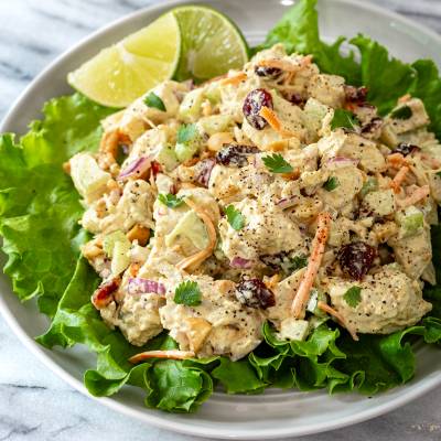 Creamy chicken salad with grapes and fresh herbs on a bed of lettuce.