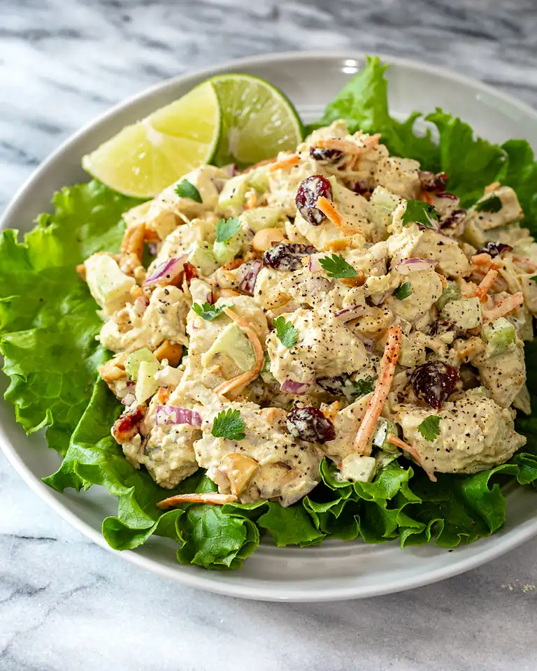 Creamy chicken salad with grapes and fresh herbs on a bed of lettuce.
