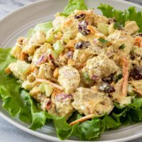 Scrambled egg salad on a bed of lettuce with vegetables and herbs.