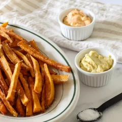 Golden crispy French fries with two dipping sauces on side.