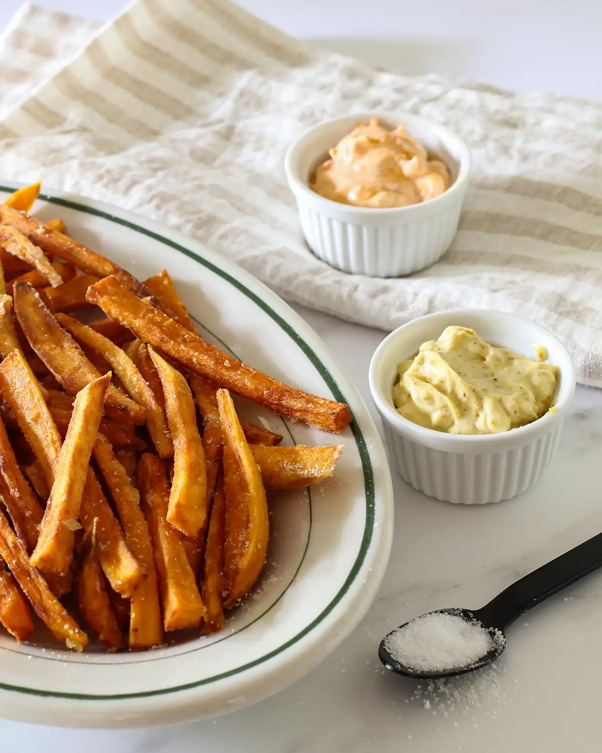Golden crispy French fries with two dipping sauces on side.