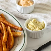Creamy mustard potato salad with herbs in a small white bowl.