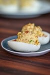 Boiled egg halves topped with creamy potato salad and paprika.