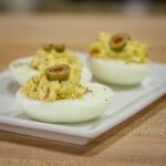 deviled eggs with olives and an olive garnish