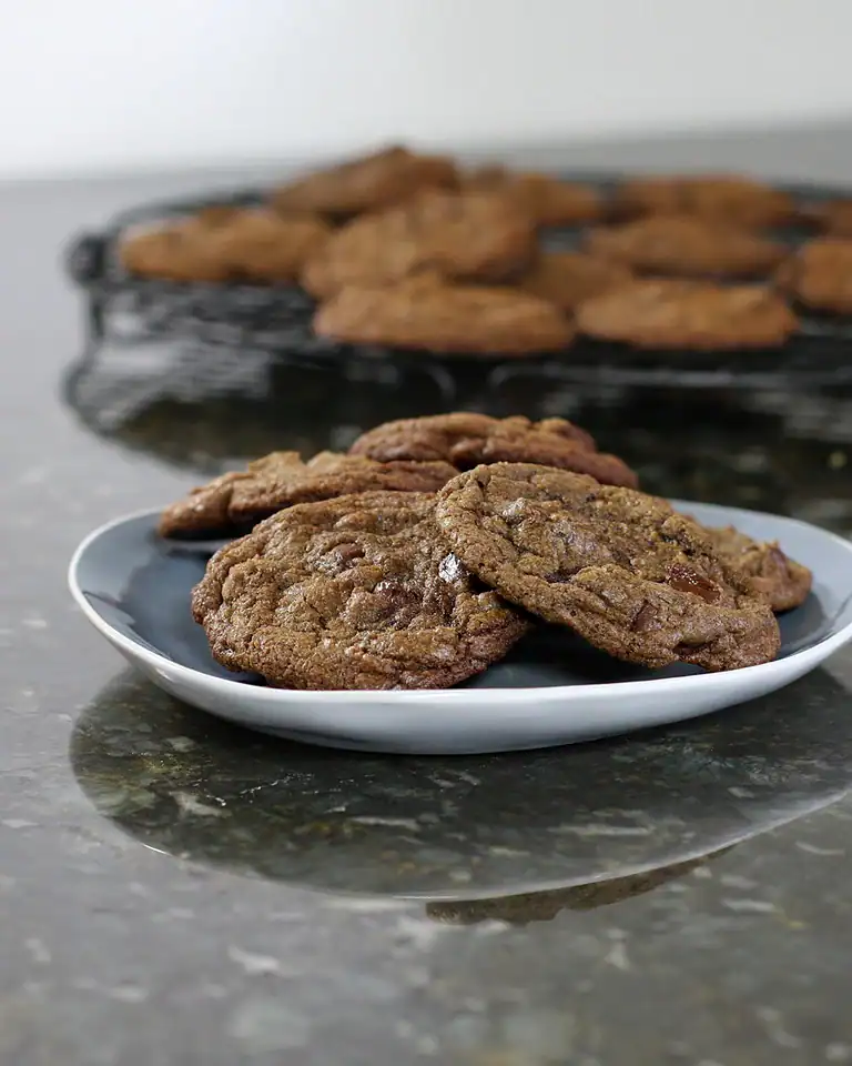 Cookies on a white plate with more cookies in the background.