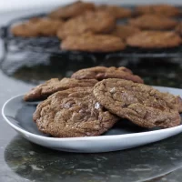 Golden brown chocolate chip cookies arranged on a white plate.