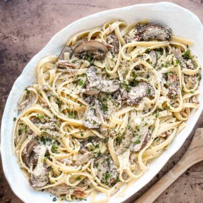 Creamy mushroom chicken Alfredo pasta on a white oval dish.