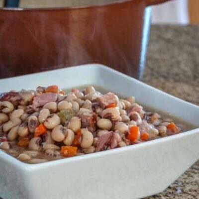 black-eyed peas in a serving dish with a dutch oven in the background