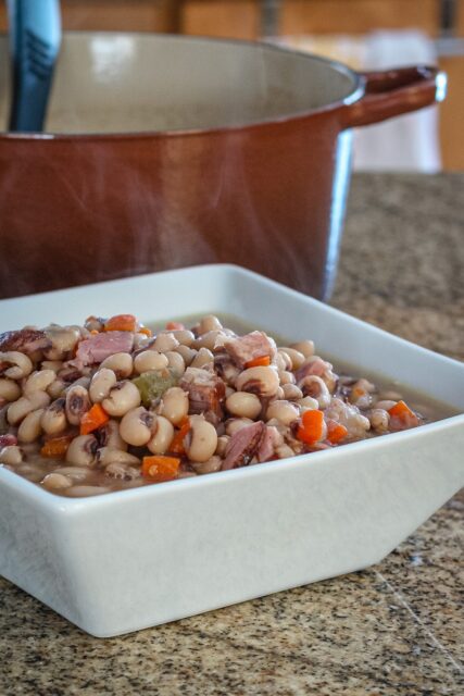 black-eyed peas in a serving dish with a dutch oven in the background