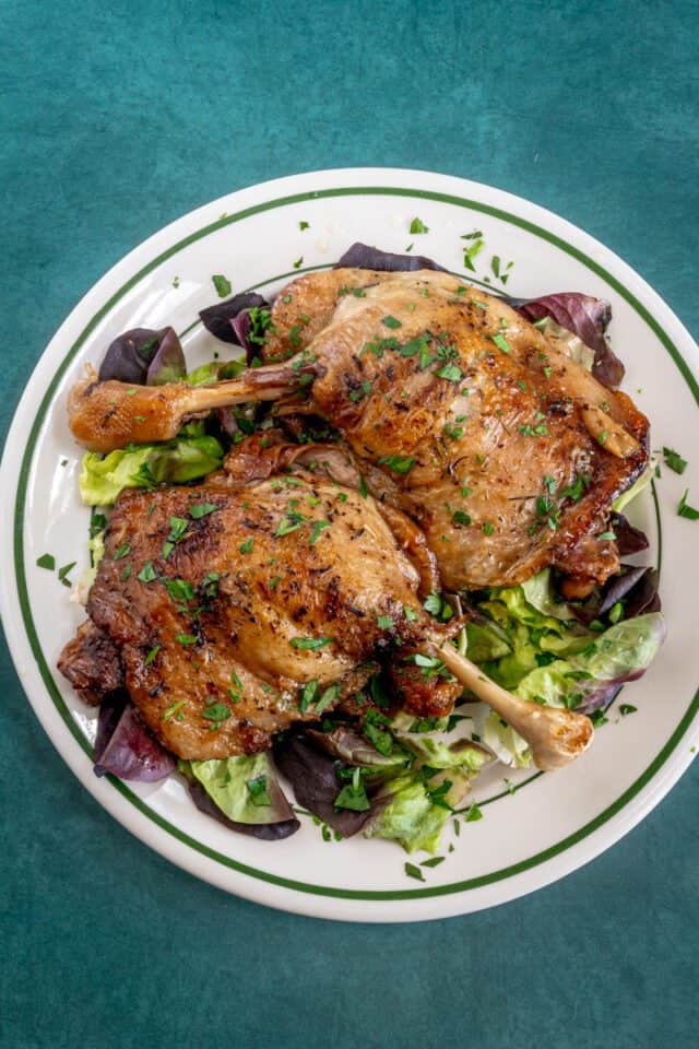 Roasted chicken drumsticks on a bed of mixed greens.