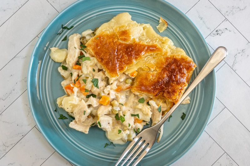 a serving of chicken pot pie and puff pastry crust on a plate with fork.