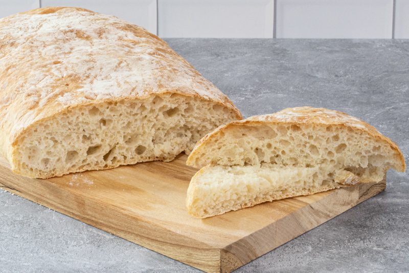 A sliced loaf of ciabatta bread showing its crust and airy texture