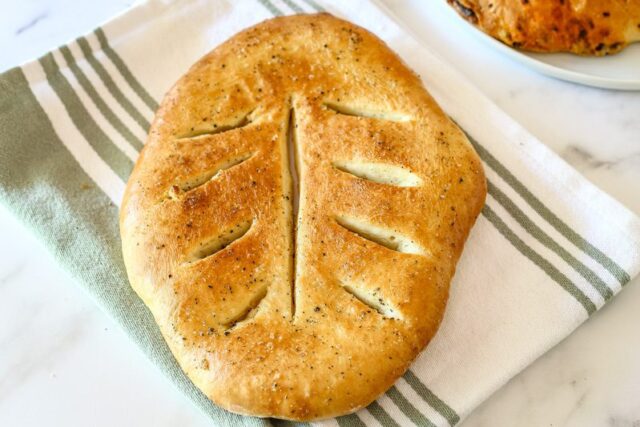 A loaf of fougasse with freshly ground black pepper and flaky sea salt.