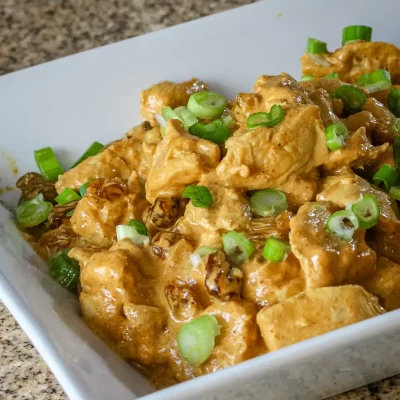 Creamy chicken and mushroom stew with green onion garnish.