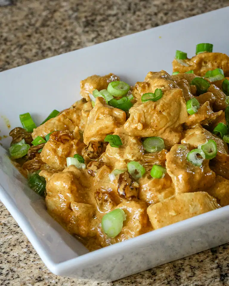 Creamy chicken and mushroom stew with green onion garnish.
