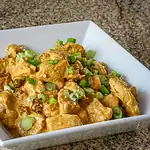 Crispy tofu with green onions in a white dish.