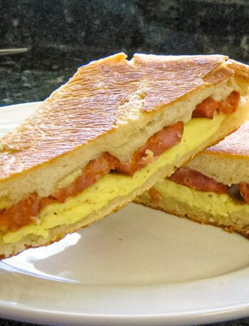 Egg, andouille sausage panini on a plate.