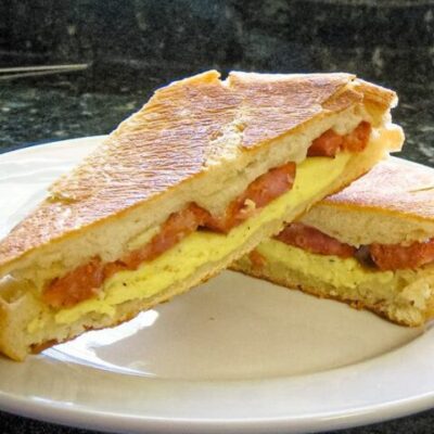Egg, andouille sausage panini on a plate.