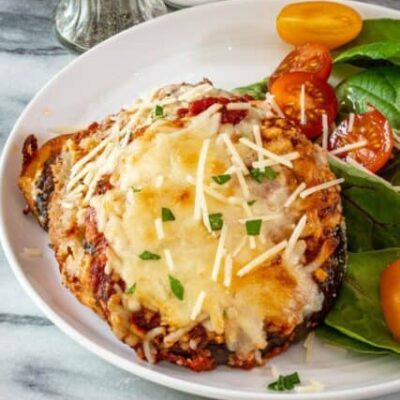 eggplant parmesan serving on a plate with salad