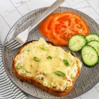 Tuna melt sandwiches, open-faced, with sliced tomatoes and cukes on the side.