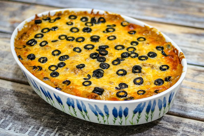 an enchilada casserole covered with cheese and sliced olives.