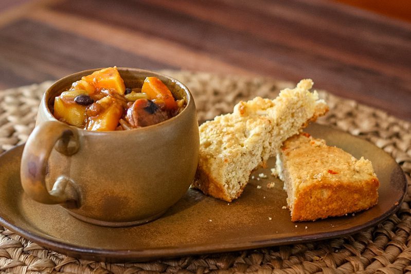 baked beans with butternut squash and smoked sausage on a plate with cornbread
