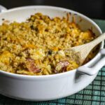 Casserole dish with baked farfalle, cheese, and smoked sausage.
