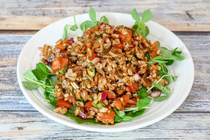 farro salad with tomatoes on a plate with pea shoots