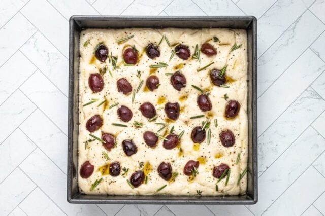 olive focaccia in a pan, ready to bake.
