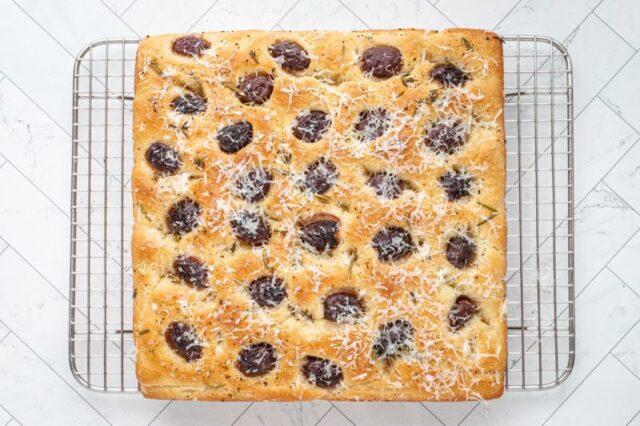 Baked olive focaccia on a cooling rack.