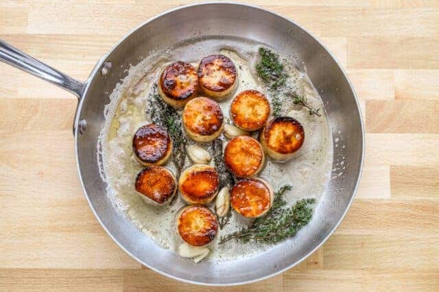 Golden seared scallops in garlic butter with herbs.