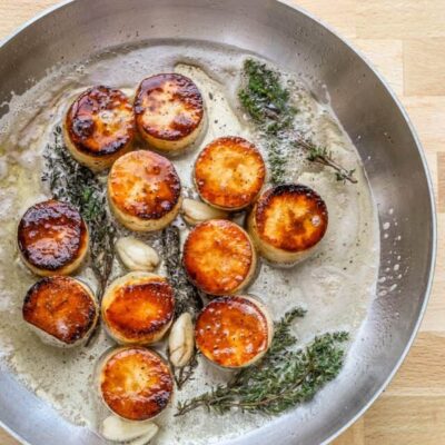 Perfectly seared scallops with garlic and herbs in a creamy sauce.