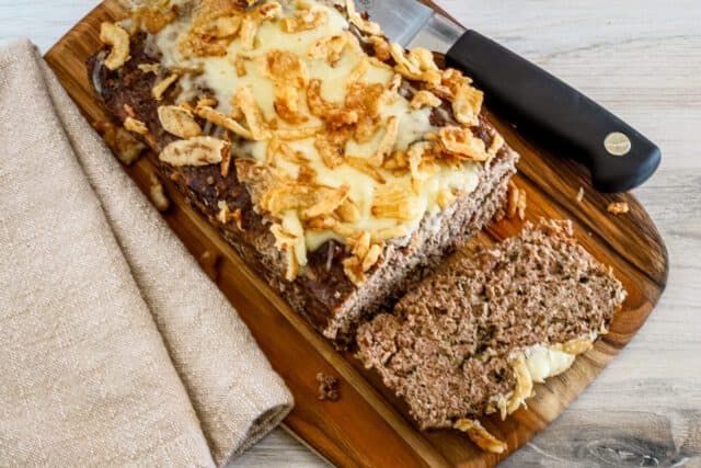 Homemade banana bread topped with melted cheese and crispy banana chips.
