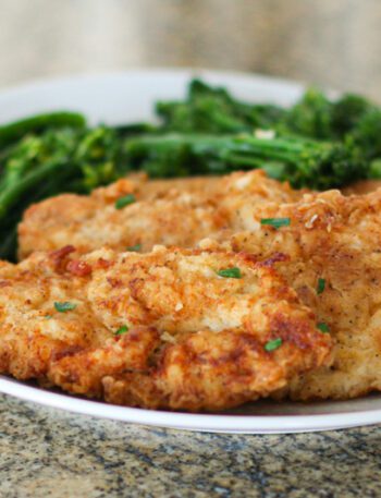 fried chicken breast cutlets on a plate with broccolini