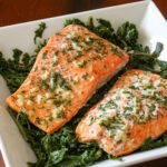 garlic and herb baked salmon shown on a bed of spinach