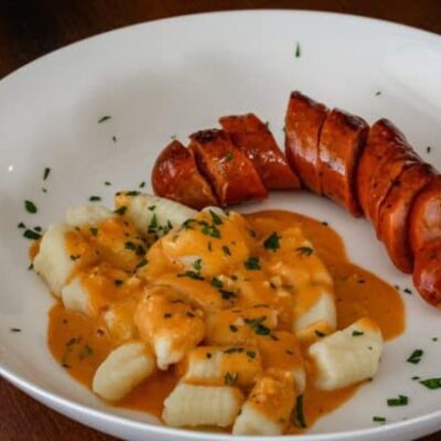 homemade gnocchi on a plate with andouille sausage and a sauce